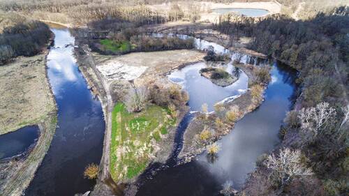 Aerial view of countryside with river ecosystem under increased flow rates.